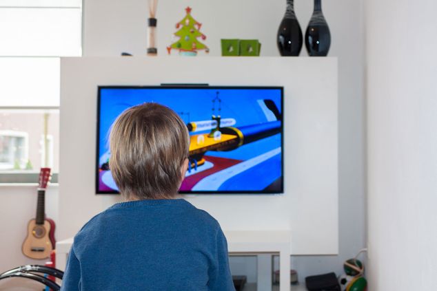 A child playing computer games on a TV mounted to a wall